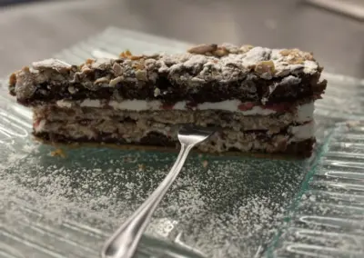 Eine Schichttorte mit Nüssen, Sahne und einer Schicht aus Marmelade auf einem Glasuntersetzer.