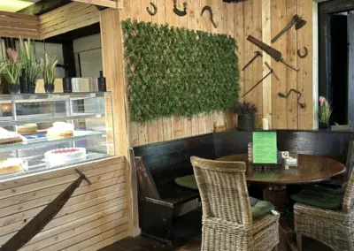 Gemütliche Restaurant-Ecke mit Holzwänden, einem runden Tisch und Stühlen aus Korbgeflecht.