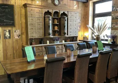 Ein großer Holztisch mit mehreren Stühlen in einem Restaurant mit rustikalem Dekor.