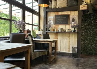 Gemütliche Restaurant-Innenansicht mit Holztischen und Stühlen sowie einer Tafel mit Speisen.